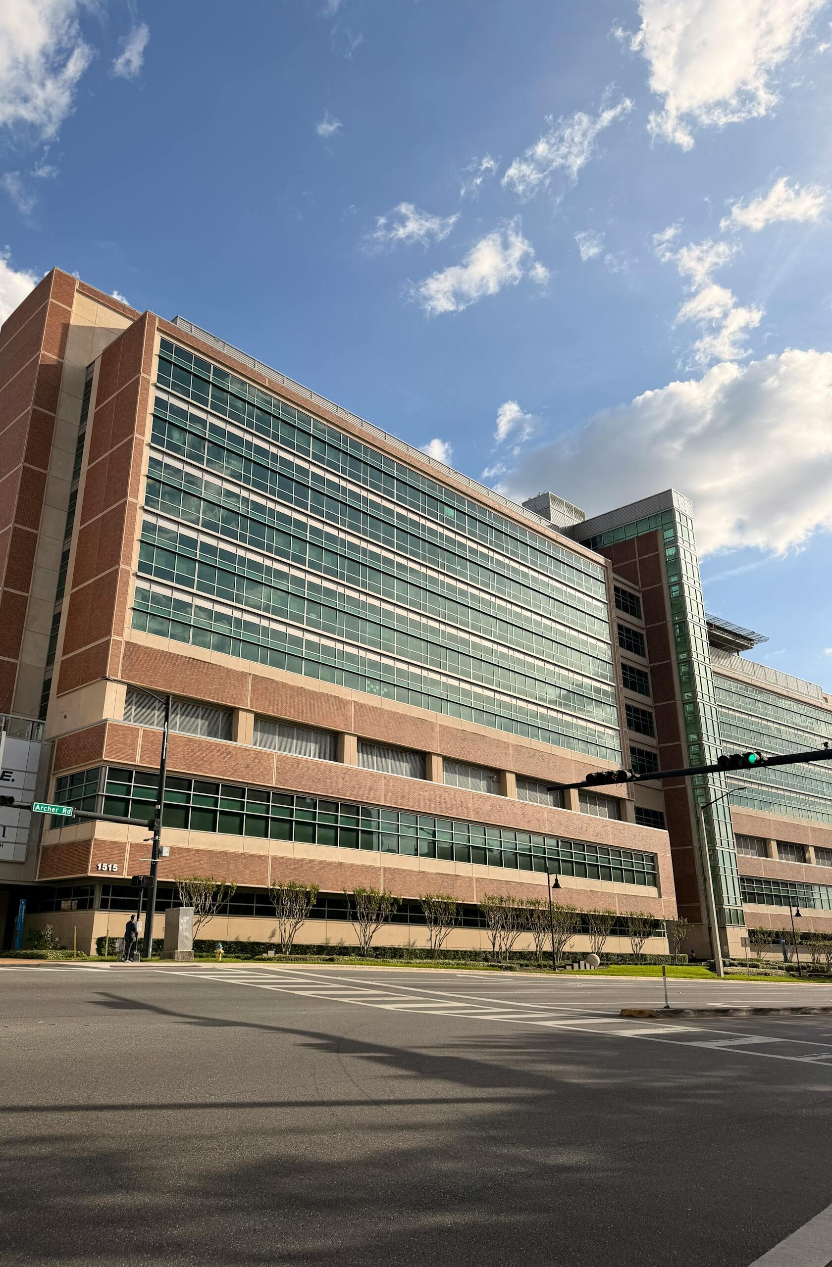 Gainesville hospital exterior with glass facade and blue sky, showcasing modern architecture.